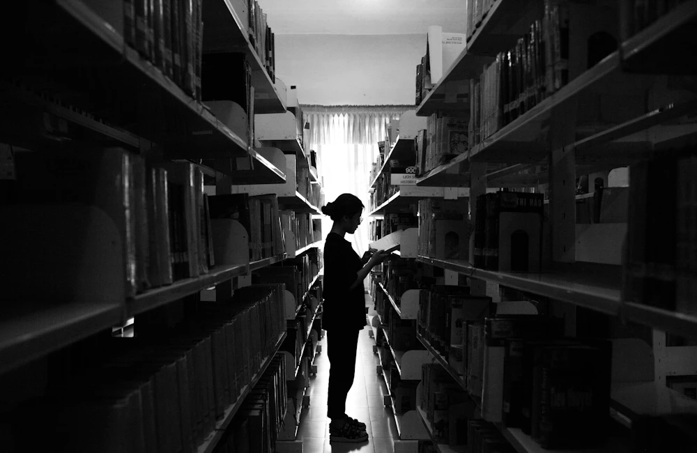 صورة توضيحية: باحث بين رفوف الكتب في مكتبة